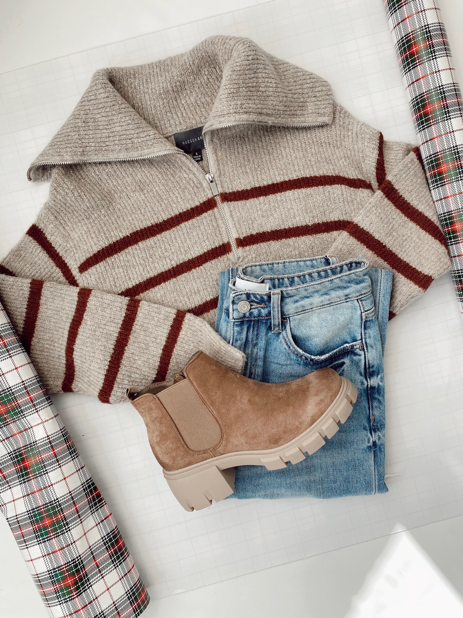 flat lay of a striped sweater and jeans with brown booties